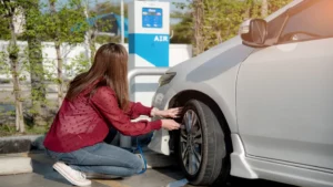 Femme vérifiant la pression des pneus d'une voiture à une borne d'air